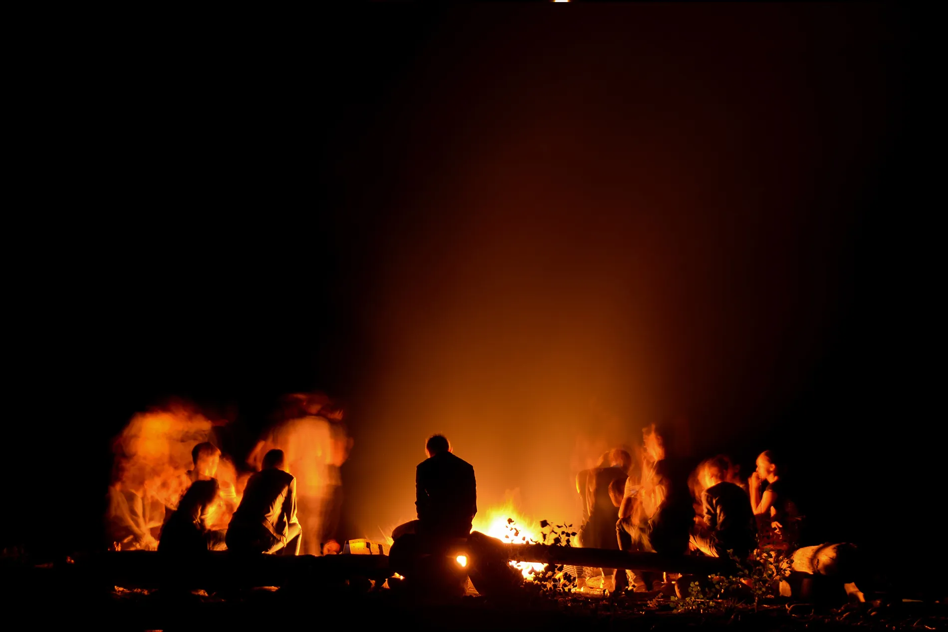The Emberworks crew, gathered around a fire at dusk